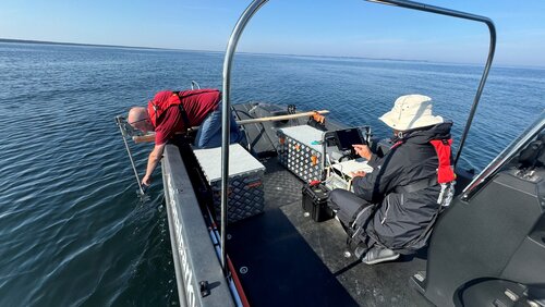 Zwei Personen sitzen in einem Boot, das mit Messungsinstrumenten ausgestattet ist