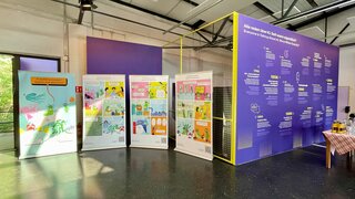 Vier Banner mit dem Seegurken Comic stehen nebeneinander in einer großen Halle.