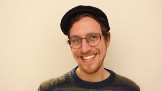 Porträt einer männlich gelesenen Person mit Brille, Dreitagebart und Kappe