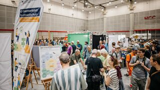Besuchende an Stand der KI-Ideenwerkstatt auf Messe Maker Faire