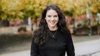 Frau mit langen dunkelbraunen Haaren lächelt