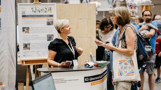 Eine Mitarbeiterin und eine Besucherin unterhalten sich am Messestand.