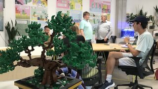 kleiner Bonsai aus Lego, im Hintergrund unscharf die Teilnehmenden an Tisch