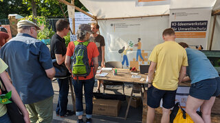 Mehrere Personen vor einem Messestand der KI-Ideenwerkstatt